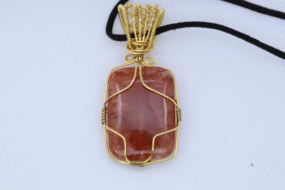 Agaat oranje achtige steen vervaardigd met goudkleurig koperdraad  en een suède koord