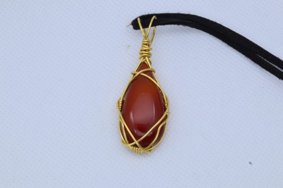 Rode steen in goudkleurige draad verwikkeld tot mooie hanger met zwart suède koord